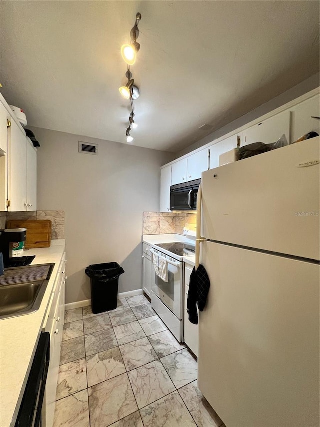 kitchen featuring decorative backsplash, sink, rail lighting, white cabinetry, and white appliances