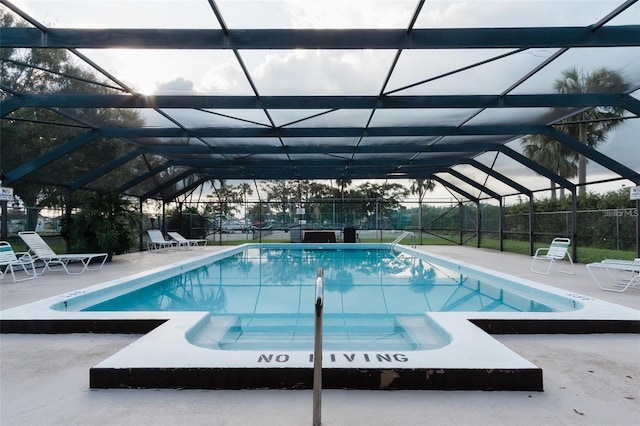 view of swimming pool featuring a patio and glass enclosure