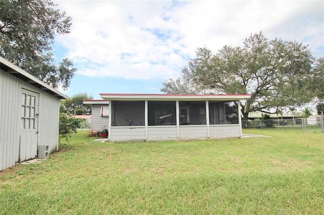 rear view of house with a sunroom and a yard