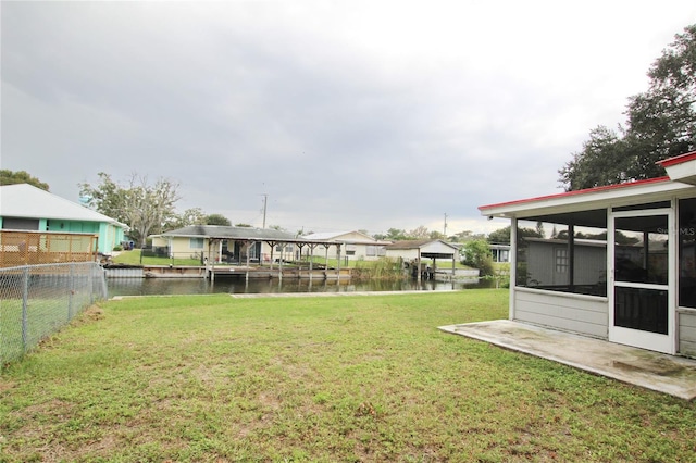 view of yard featuring a sunroom and a water view