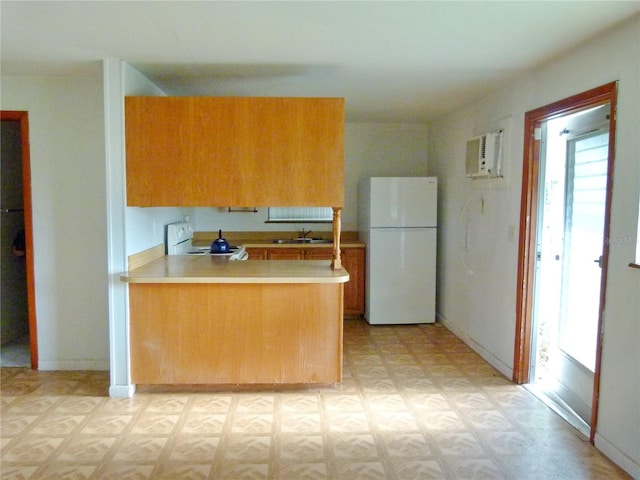 kitchen featuring sink, kitchen peninsula, a wall mounted air conditioner, white appliances, and light parquet floors