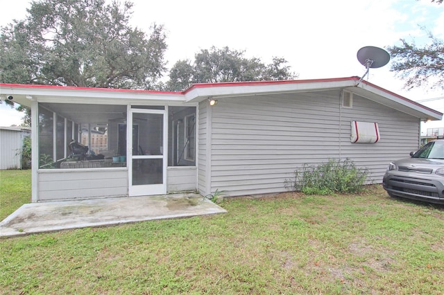 back of house with a lawn, a patio, and a sunroom