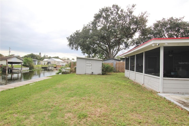 view of yard featuring a shed, a water view, and a sunroom