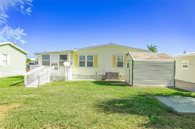 back of property with a yard, an outdoor structure, and central air condition unit