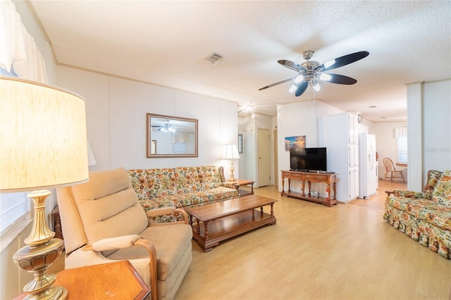 living room with ceiling fan, light hardwood / wood-style flooring, and a textured ceiling