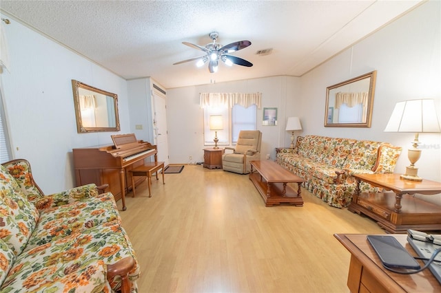 living room with ceiling fan, light hardwood / wood-style floors, lofted ceiling, and a textured ceiling