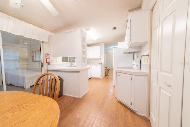 kitchen featuring white cabinetry, light hardwood / wood-style flooring, a textured ceiling, and sink