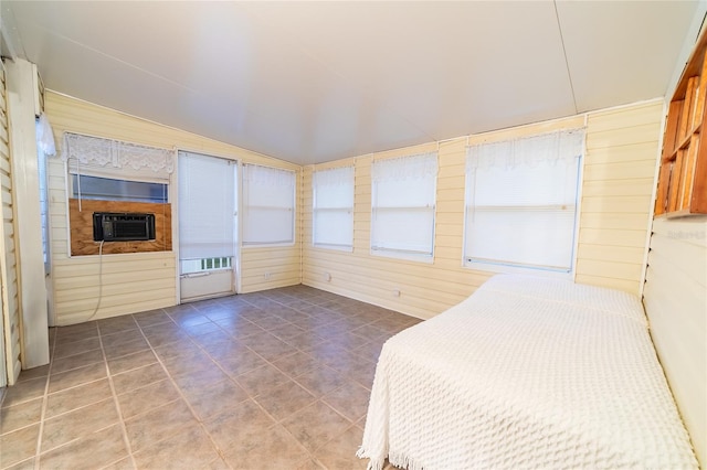 unfurnished bedroom featuring tile patterned floors, wood walls, and vaulted ceiling