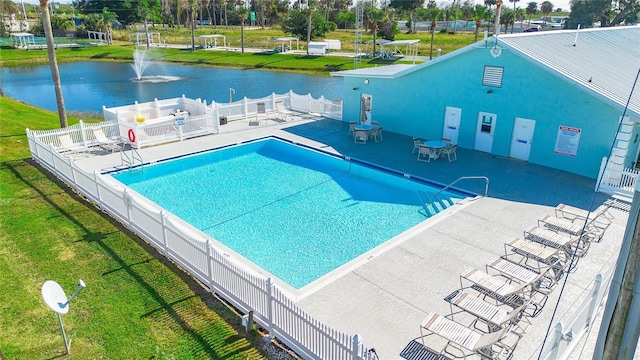 view of pool featuring a patio, a water view, and a lawn