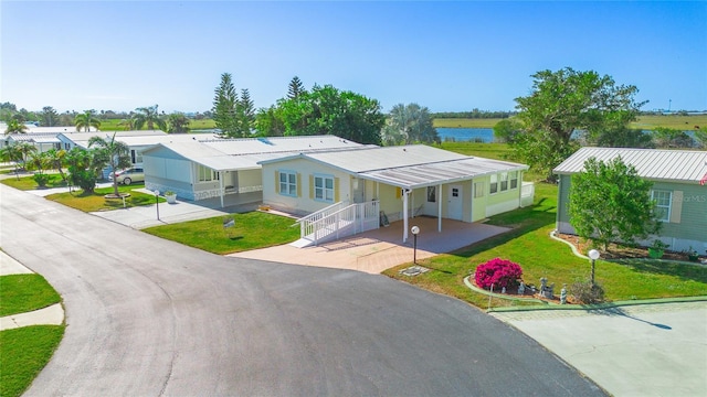 view of front of home with a carport, a water view, and a front yard