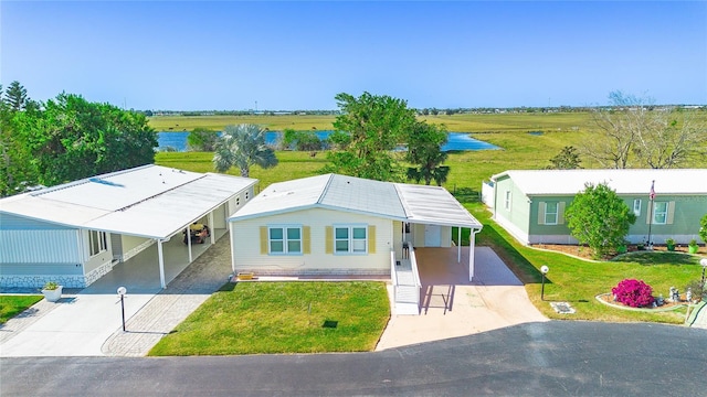 view of front of home featuring a front lawn, a water view, and a carport