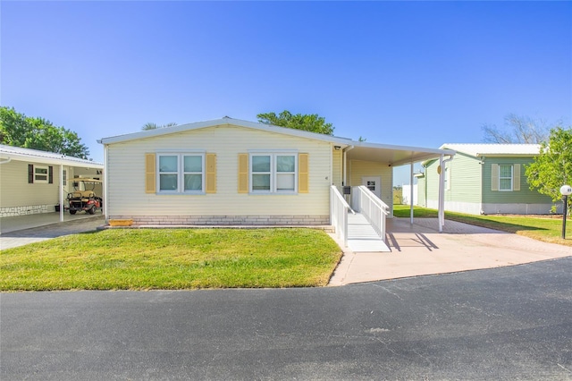 manufactured / mobile home with a carport and a front yard