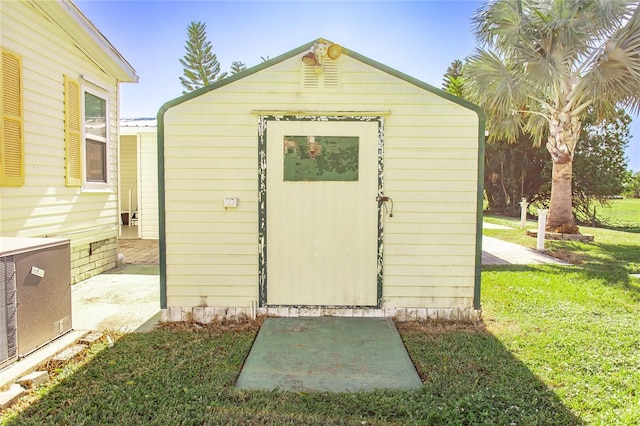 view of outbuilding featuring central AC unit and a lawn