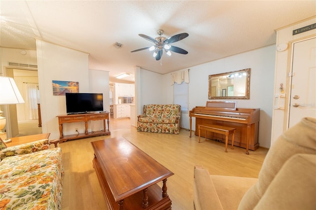 living room with ceiling fan, light hardwood / wood-style floors, and a textured ceiling