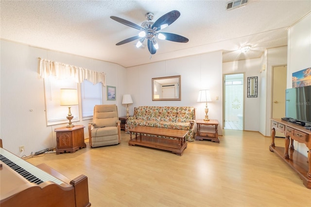 living room featuring ceiling fan, light hardwood / wood-style floors, and a textured ceiling