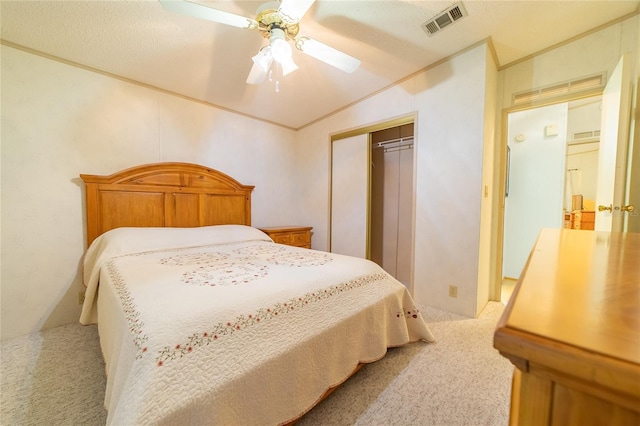 bedroom featuring ceiling fan, light colored carpet, a textured ceiling, lofted ceiling, and a closet