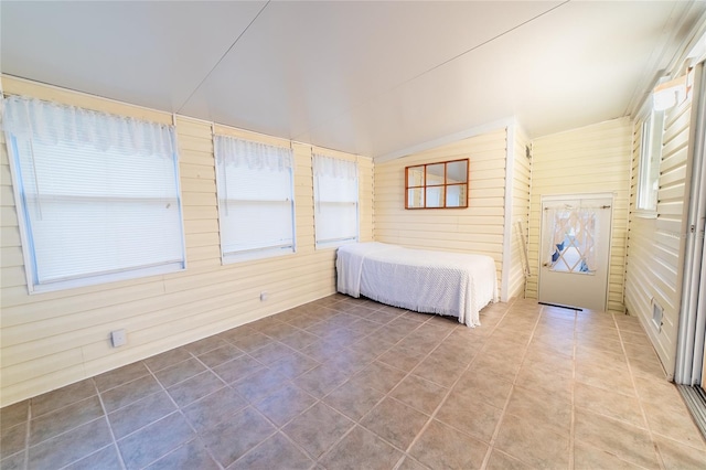 unfurnished bedroom with tile patterned floors and wooden walls