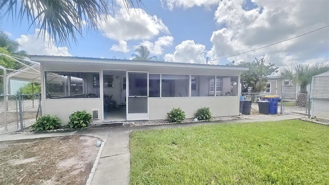 rear view of property with a yard and a sunroom