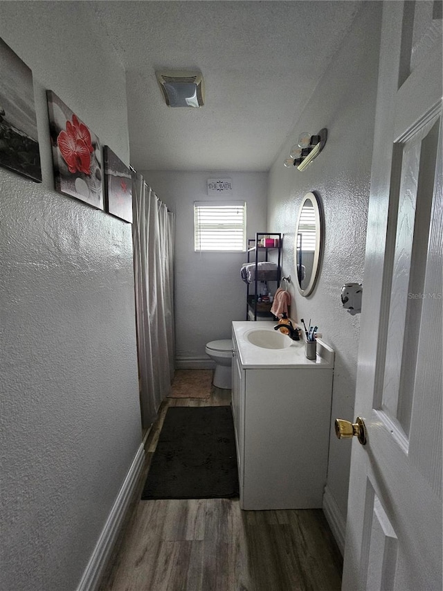 bathroom with a shower with curtain, vanity, a textured ceiling, hardwood / wood-style floors, and toilet