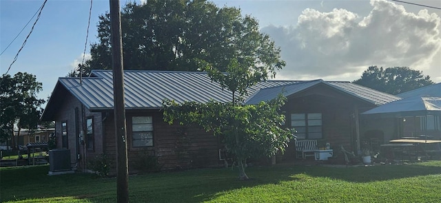 rear view of house featuring a lawn and central air condition unit