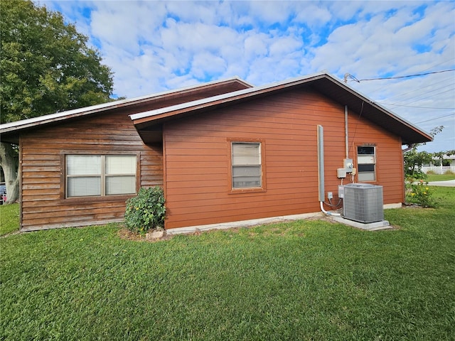 view of side of home with central AC unit and a lawn