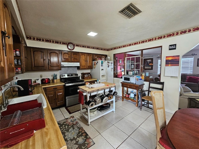 kitchen with dark brown cabinets, white appliances, a textured ceiling, sink, and light tile patterned floors