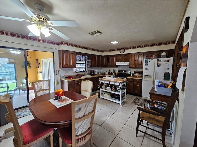 kitchen with white refrigerator with ice dispenser, dark brown cabinetry, ceiling fan, and stainless steel electric range