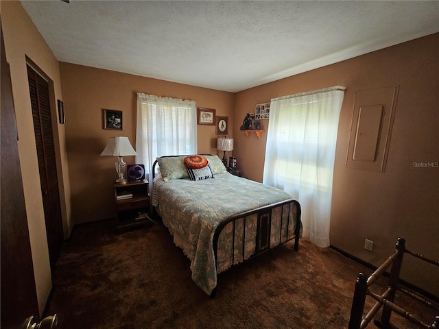 bedroom with dark colored carpet, a textured ceiling, and a closet