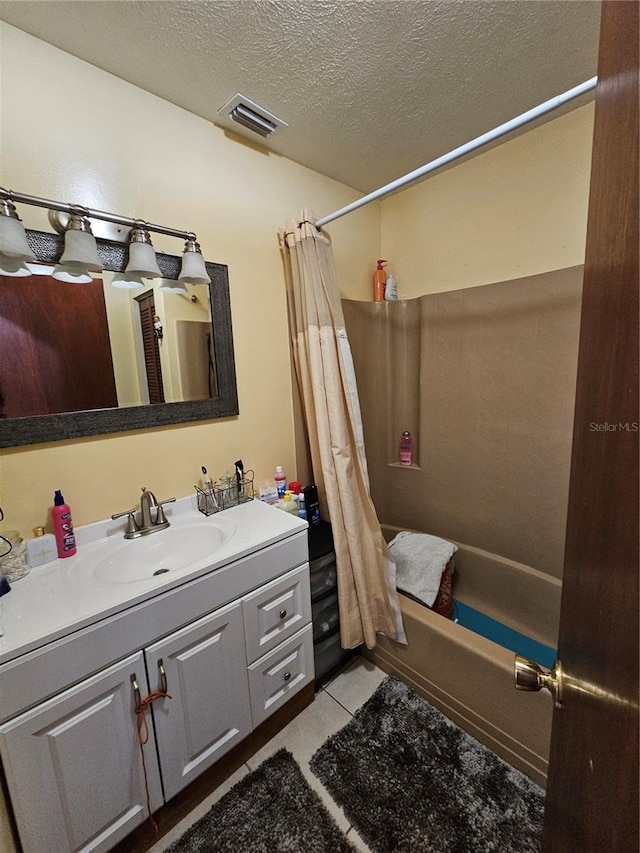 bathroom with tile patterned flooring, vanity, a textured ceiling, and shower / tub combo