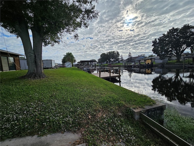 dock area with a lawn and a water view