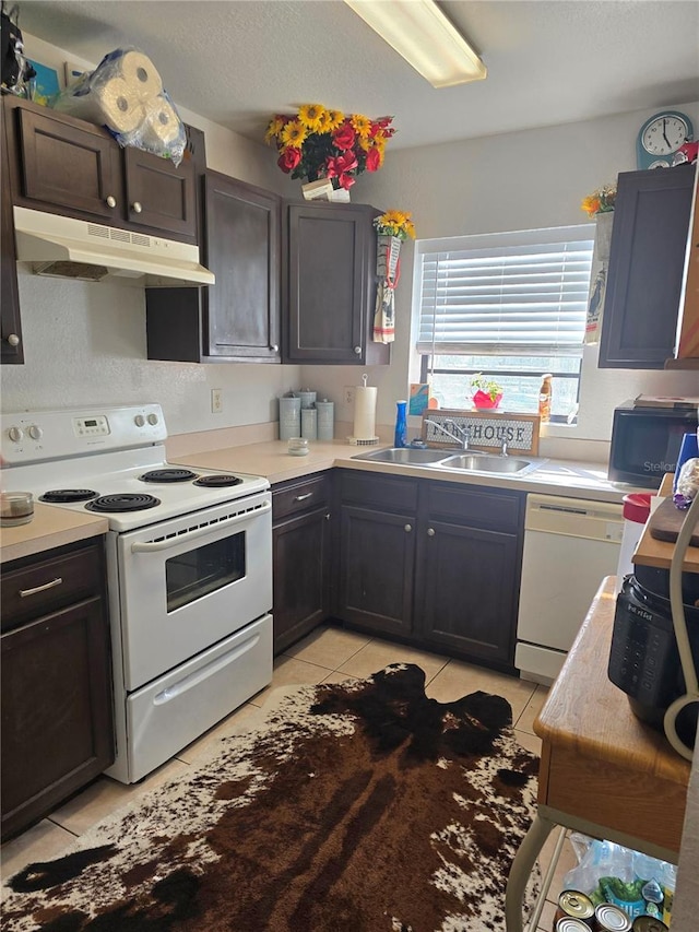 kitchen with dark brown cabinets, sink, light tile patterned floors, and white appliances