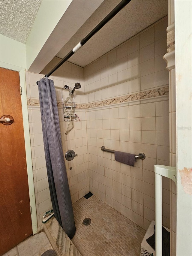 bathroom with a textured ceiling, curtained shower, tile patterned flooring, and tile walls