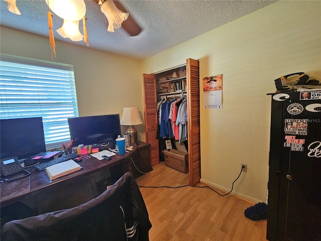 home office with ceiling fan, light hardwood / wood-style flooring, and a textured ceiling