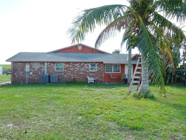 rear view of house featuring a lawn and central air condition unit