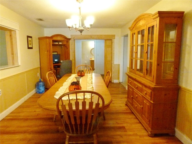 dining area with hardwood / wood-style floors and an inviting chandelier