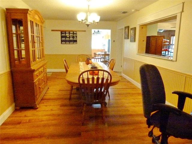 dining space with hardwood / wood-style flooring, plenty of natural light, and a chandelier