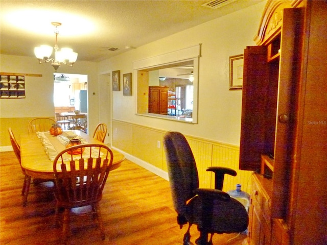 dining space with ceiling fan with notable chandelier and hardwood / wood-style flooring