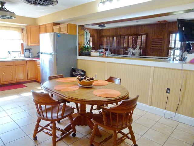 tiled dining room with wooden walls, plenty of natural light, and sink