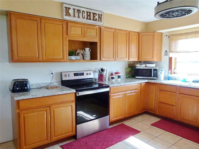 kitchen with appliances with stainless steel finishes, light stone counters, and light tile patterned flooring