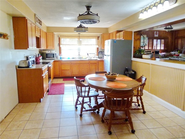 kitchen featuring wooden walls, decorative light fixtures, light tile patterned floors, and appliances with stainless steel finishes