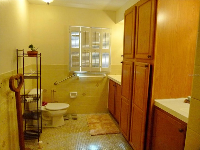 bathroom with tile patterned floors, vanity, toilet, and tile walls