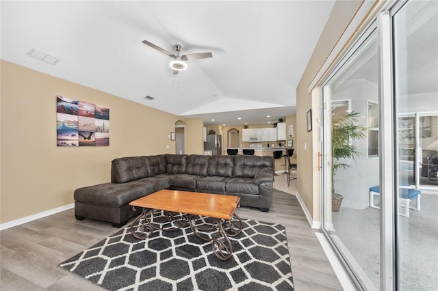 living room featuring ceiling fan, light wood-type flooring, and vaulted ceiling