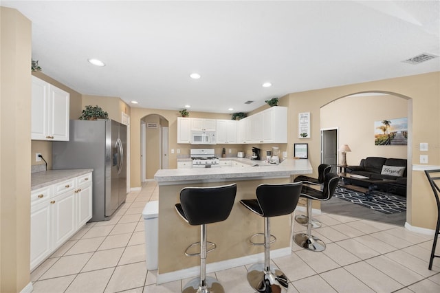 kitchen with white cabinets, white appliances, kitchen peninsula, and light tile patterned floors