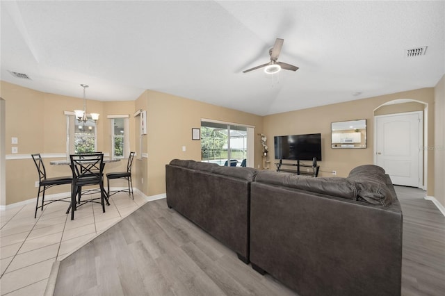 living room featuring ceiling fan with notable chandelier and light wood-type flooring