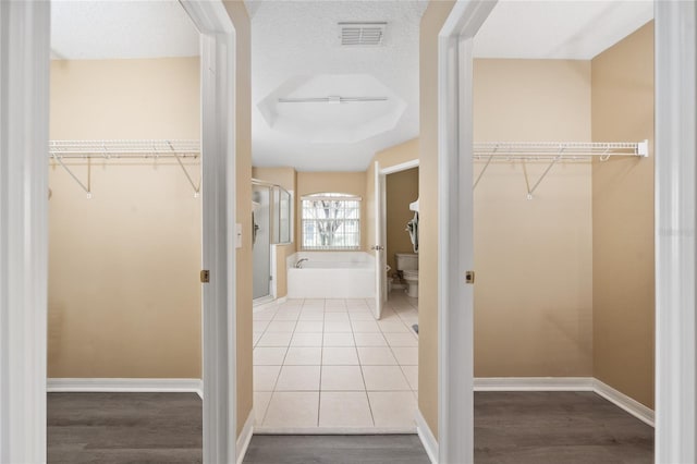 bathroom with a washtub, a textured ceiling, hardwood / wood-style flooring, and toilet