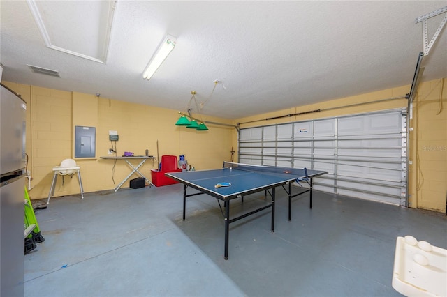 recreation room featuring concrete flooring, a textured ceiling, and electric panel