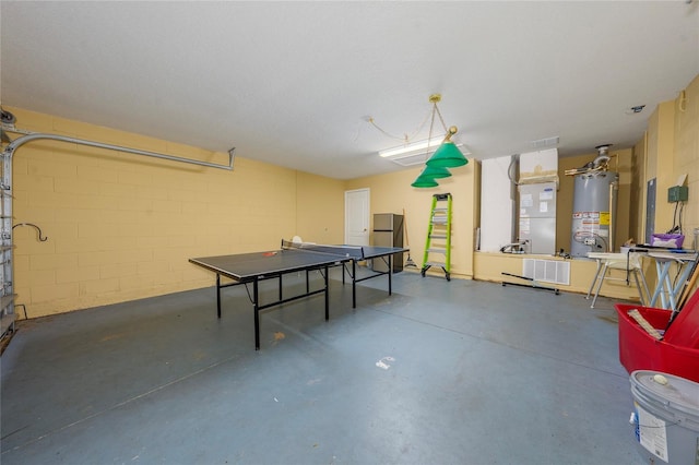 game room with heating unit, a textured ceiling, and water heater