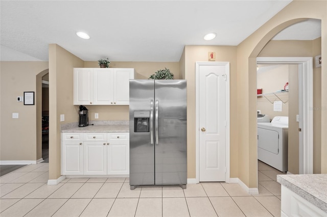 kitchen with washing machine and clothes dryer, white cabinetry, light tile patterned floors, and stainless steel refrigerator with ice dispenser