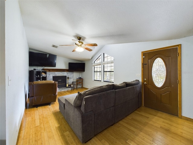 living room with a fireplace, light hardwood / wood-style flooring, ceiling fan, and lofted ceiling