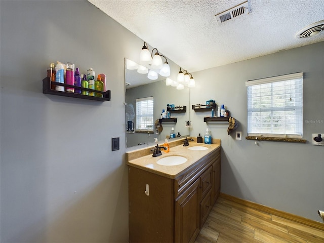 bathroom with hardwood / wood-style floors, vanity, a healthy amount of sunlight, and a textured ceiling